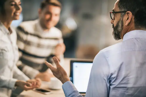 Photo of Profile view of mature insurance agent talking to a couple in the office.