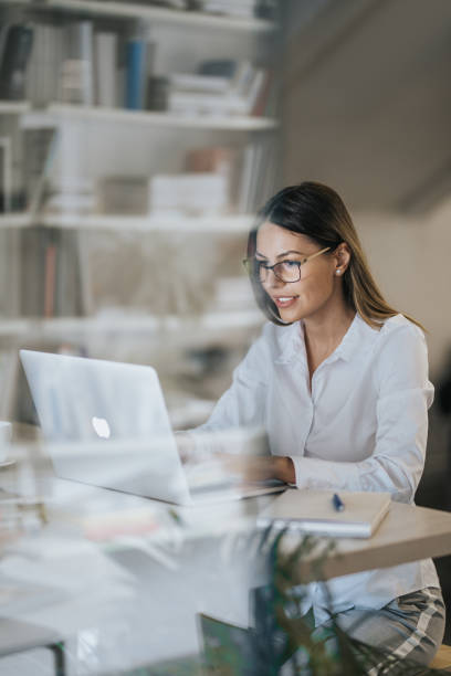 szczęśliwa bizneswoman wpisując e-mail na laptopie w domowym biurze. - wireless technology working at home one person reading zdjęcia i obrazy z banku zdjęć