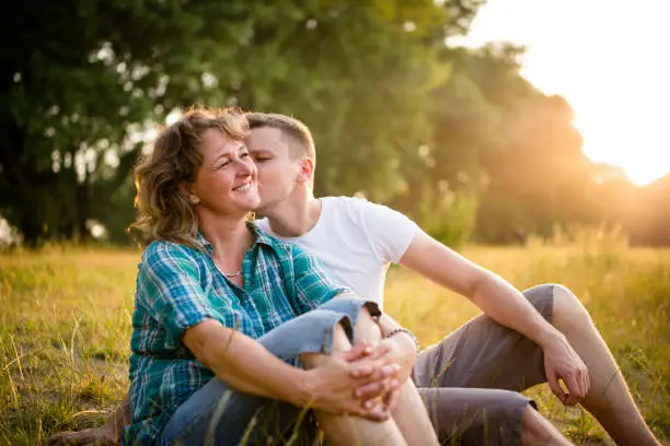 Young adult boy kissing her mother on cheek