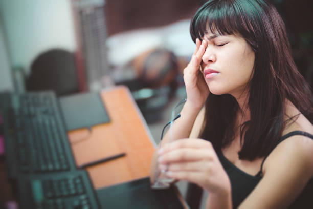 Young woman with aching eyes after working on computer. Asian, Indian young woman rubbing her eye and holding eyeglasses. She is suffering with aching eyes while working long hours on computer at home. tired after work stock pictures, royalty-free photos & images