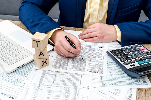 Businessman  filling W-4 form with pen, calculator and pc