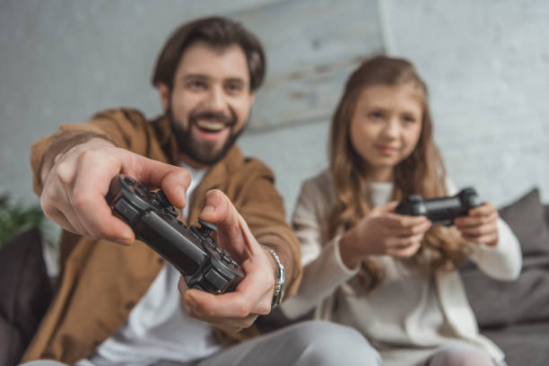 istock smiling father and daughter playing video game with focus on joysticks 942154640