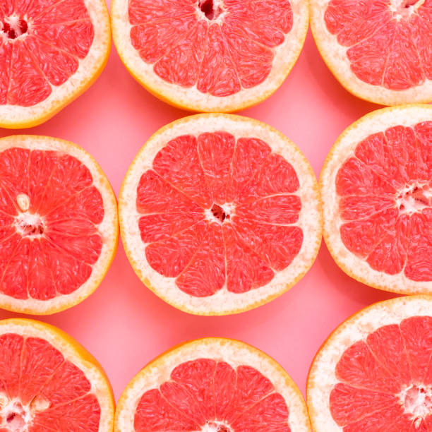 istock Background of grapefruits split in half on a pink background 942156886