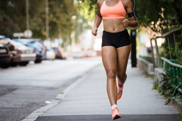 Cropped image of a woman jogger on sidewalk, wearing armband. stock photo
