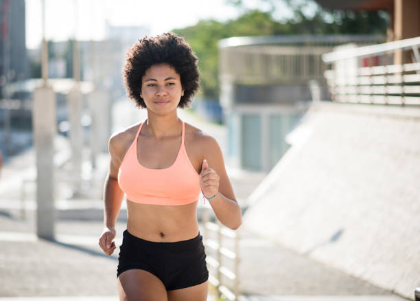 istock Running woman. Runner is jogging in sunny bright daylight. 942158022