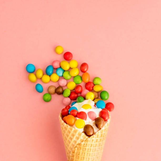 istock Ice cream in a waffle cone with colored candy toppings on a pink background 942158790