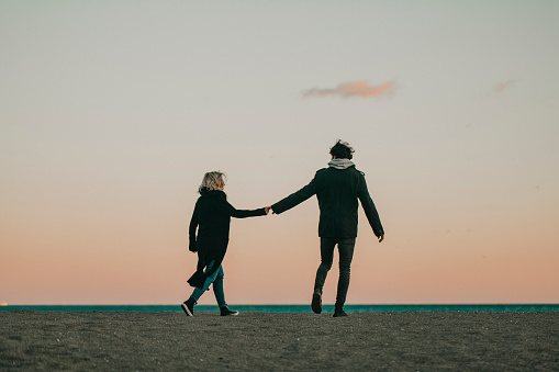 Young couple taking a walk on the beach at evening.