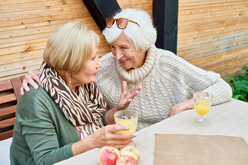 Portrait of two senior women chatting happily  enjoying lunch outdoors, copy space