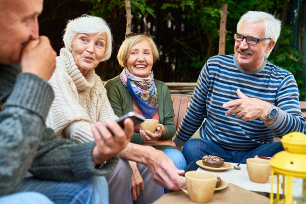 Senior Friends Enjoying Time Outdoors Group of cheerful seniors enjoying time together drinking tea outdoors in cafe and sharing life stories in retirement group of objects stock pictures, royalty-free photos & images