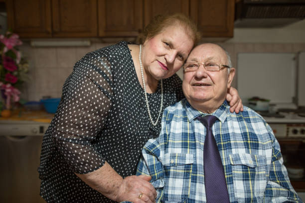 sechzig jahre zusammen. gerne älteres paar im wohnzimmer - overweight smiling senior women 70s stock-fotos und bilder