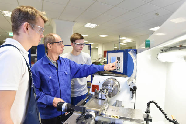 young apprentices in technical vocational training are taught by older trainers on a cnc lathes machine - built structure education school education building imagens e fotografias de stock