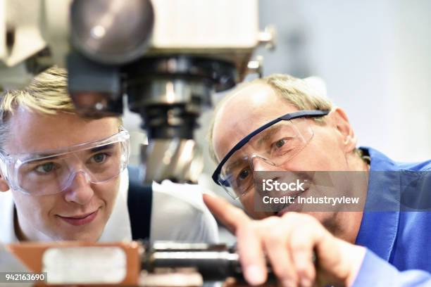 Closeup Picture Trainer And Apprentice In Vocational Training On A Milling Machine Teacher Explains Details Of The Machine Stock Photo - Download Image Now