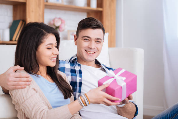 istock Man presenting surprise to cheerful woman 942164162