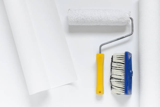 istock paint roller and a brush on white wallpaper roll 942166778