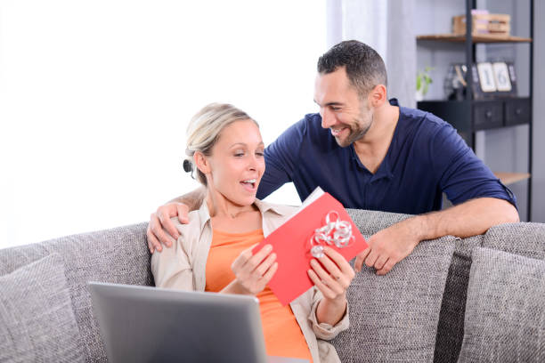 istock handsome man offering surprise present invitation in envelope gift to his young woman valentine girlfriend 942169700