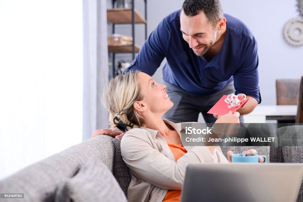 handsome man offering surprise present invitation in envelope gift to his young woman valentine girlfriend Gift Certificate or Card Stock Photo