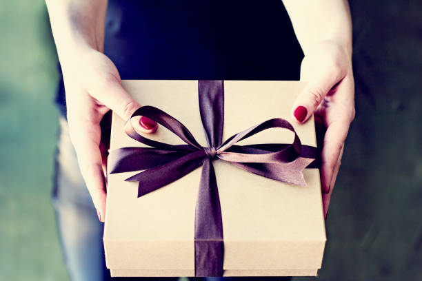istock Female hands hold a crafted box with a gift. 942176674