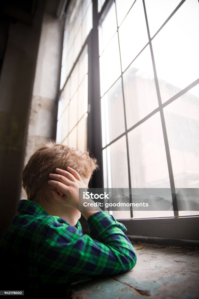 Niño De Pie Detrás De La Ventana De Estado De Ánimo Triste Adolescente Triste Mirando En La Ventana Y Cierre Sus Oídos Con Las Manos Niño Infeliz En Una Camisa A Cuadros Niño De Pie Detrás De La Ventana De Estado De Ánimo Triste Adolescente Triste Mirando En La Ventana Y Cierre Sus Oídos Con Las Manos Niño Infeliz En Una Camisa A Cuadros