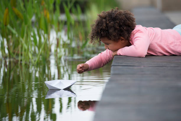 istock Afro curly kid playing paper boat. 942178048