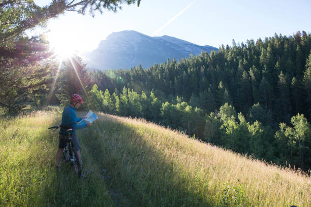 istock Man pauses in mountain meadow with map 942179486