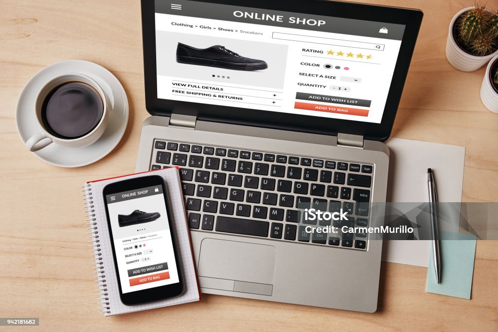 Online shop concept on laptop and smartphone screen Online shop concept on laptop and smartphone screen over wooden table. All screen content is designed by me. Flat lay E-commerce Stock Photo