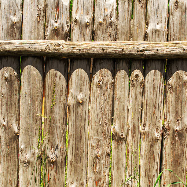 istock Old weathered log wall. Wooden fence from old vertical logs. Square. 942183062