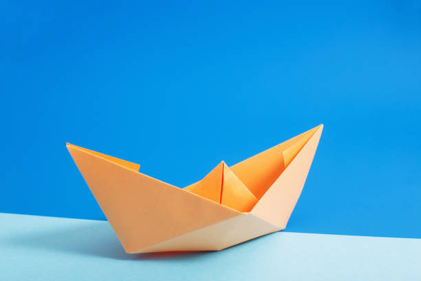 istock paper boat on blue paper background 942183802