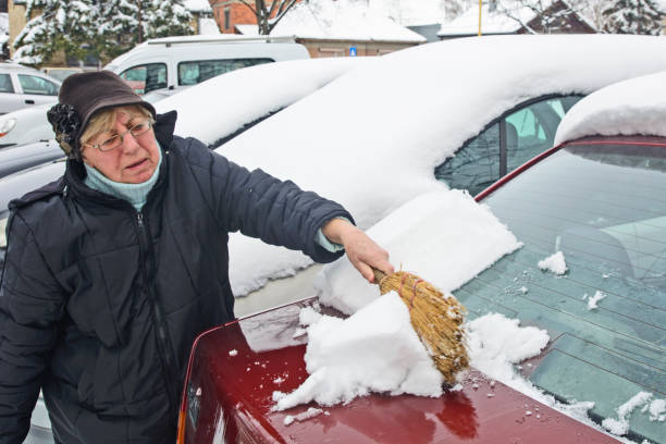 istock Woman driver cleans the snow from the car 942185538