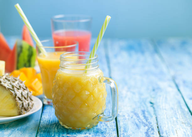 istock Fresh pineapple and watermelon smoothie in three glasses on a blue wooden rustic background 942187372