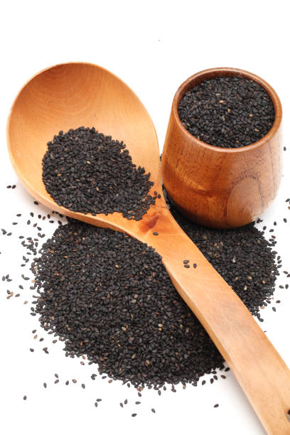 istock Black sesame in wooden spoon isolated on white background 942188786