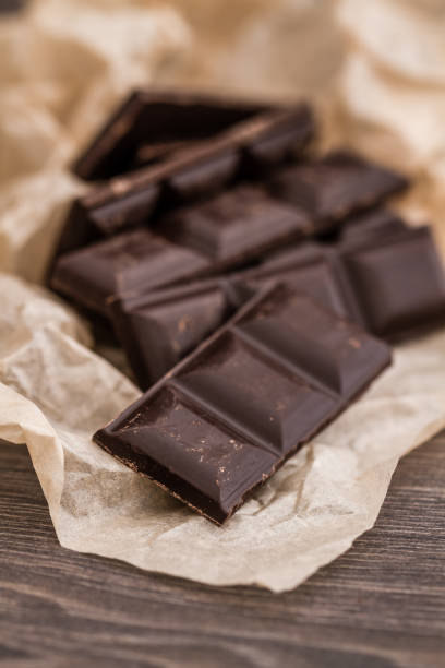 istock Dark Chocolate Bars on Crumbled Paper and Wooden Table 942191250