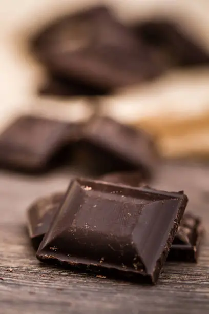 Dark Chocolate bars on crumbled paper and brown wooden background