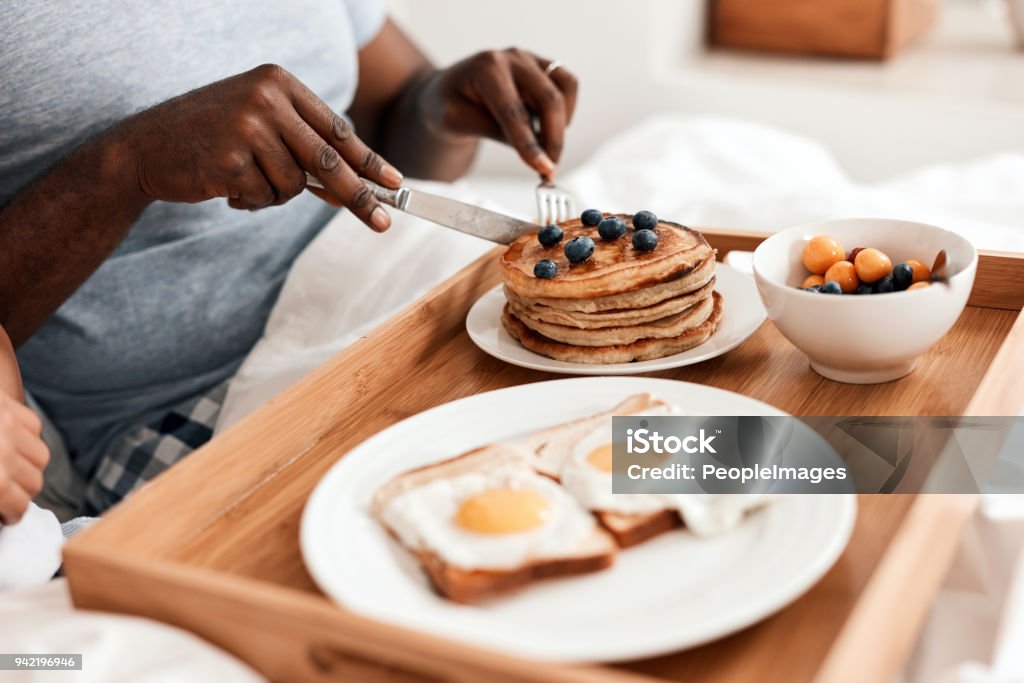 Everything you'll need to start the day with right Shot of an unrecognizable couple enjoying breakfast in bed together at home during the day Bed - Furniture Stock Photo