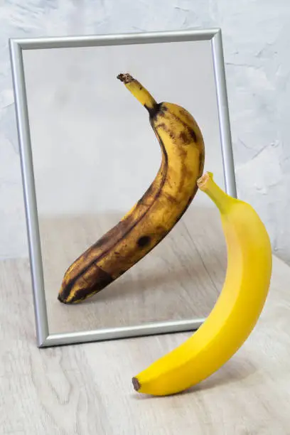 The mirror reflects a spoiled banana. Concept: stress, fatigue, sickness, old age.