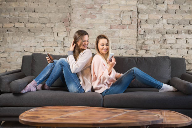 istock Young women sitting on the sofa and texting 942200716