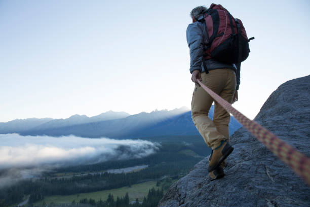 male mountaineer traverses mountain ridge at sunrise canadian rockies - backpack one mature man only only mature men one man only imagens e fotografias de stock