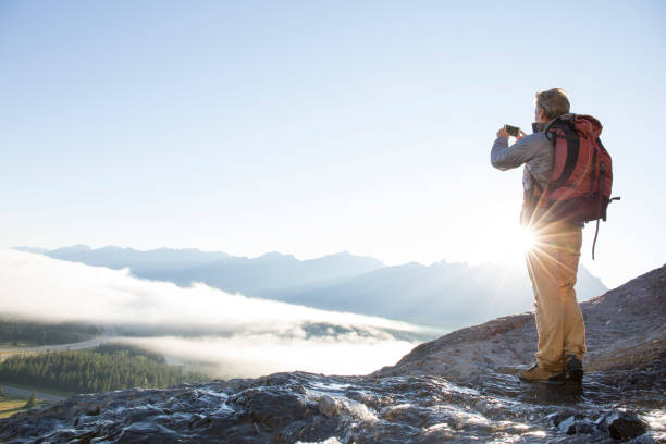istock Mountaineer takes smart phone pic above mountains, sunrise 942201082