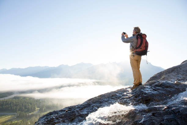 alpinista lleva pic teléfono inteligente encima de montañas, amanecer - travel destinations mountain hiking profile fotografías e imágenes de stock