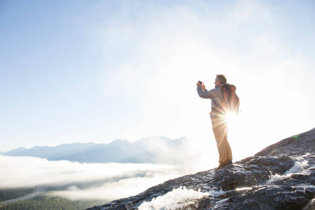 istock Mountaineer takes smart phone pic above mountains, sunrise 942201720