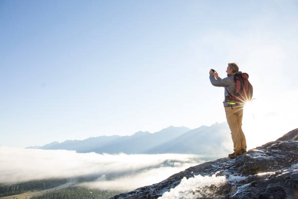 alpinista lleva pic teléfono inteligente encima de montañas, amanecer - travel destinations mountain hiking profile fotografías e imágenes de stock