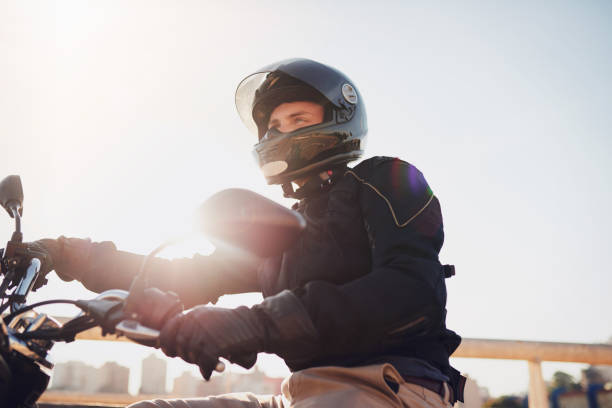 It's just you and the road Shot of a young man riding a motorbike through the city crash helmet photos stock pictures, royalty-free photos & images