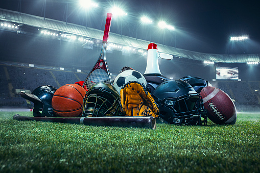 Pelotas de deportes en el campo con la línea de la yarda. Balón de fútbol, fútbol americano y béisbol en guante amarillo sobre verde hierba. Al aire libre photo