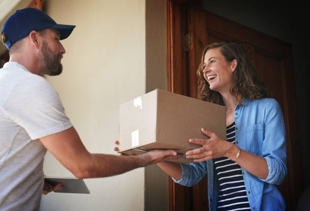 You're here quicker than I expected Shot of a courier making a delivery to a customer at her home delivery person stock pictures, royalty-free photos & images
