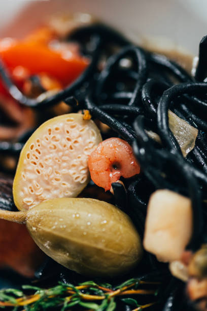 close-up view of spaghetti with cuttlefish ink, squid and mussels with octopus close-up view of spaghetti with cuttlefish ink, squid and mussels with octopus cooked selective focus vertical pasta stock pictures, royalty-free photos & images