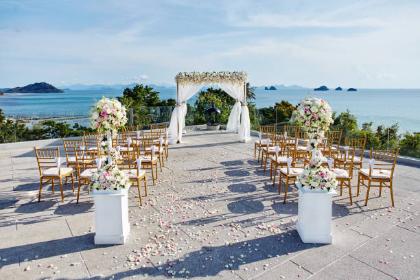 istock Wedding venue setting  on the hill, white chairs with flowers decoration, ocean background 942214272