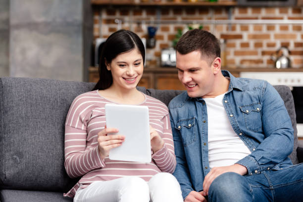 istock smiling young pregnant couple using digital tablet together at home 942214348