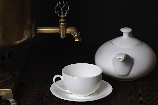 Tea cup, teapot and samovar on a dark background. Close-up, selective focus