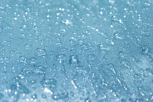 942217802 istock La lluvia cae sobre el fondo de cristal azul bokeh, brillantes gotas de lluvia sobre una superficie de vidrio, gotas de agua en un primer plano de la piscina 942217802