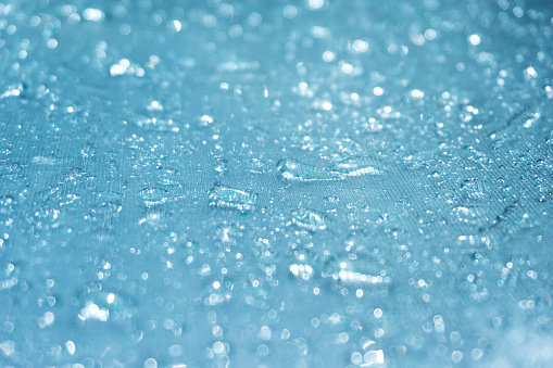 942217848 istock La lluvia cae sobre el fondo de cristal azul bokeh, brillantes gotas de lluvia sobre una superficie de vidrio, gotas de agua en un primer plano de la piscina 942217848