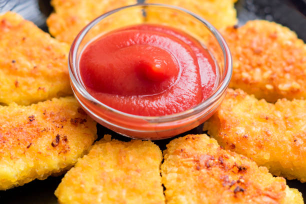 istock Fried crispy chicken nuggets with ketchup on black plate 942218468